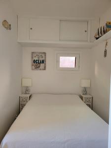 a white bed in a small bedroom with two lamps at Casa Tiemme Vista Mare in Costa Paradiso