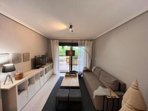 Una sala de estar con un sofá y un televisor. en Casa Ra Sol, en Orihuela Costa