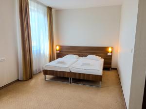 a bedroom with a bed with white sheets and a window at Hotel Arman in Nižná