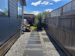 a garden with a stone walkway next to a house at Luxurious 1BR Mountain Retreat with Spa Pool in Queenstown Airport +6 photos