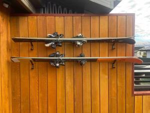 two snowboards are hanging on a wooden wall at Luxurious 1BR Mountain Retreat with Spa Pool in Queenstown Airport