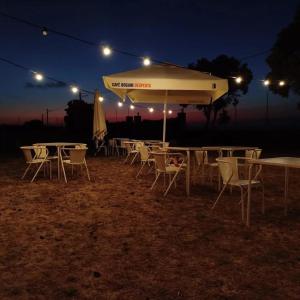a group of tables and chairs under an umbrella at night at North Coast Camping in Biscoitos