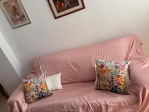 a pink leather couch with two pillows on it at Apartamento Vacacional Oropesa del Mar primera línea in Oropesa del Mar