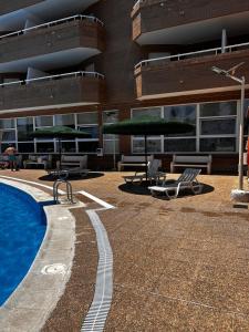a large building with a swimming pool and chairs and umbrellas at Apartamento Vacacional Oropesa del Mar primera línea in Oropesa del Mar