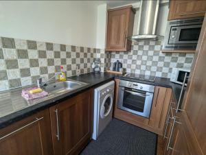a kitchen with a sink and a washing machine at Newcastle Riverside Executive Apartment in Newcastle upon Tyne
