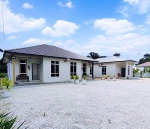 a small white house with a gravel driveway at Mukmin 2 Stay in Malacca
