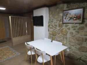a white table and chairs in a room with a stone wall at Casa do Cortinhal in Covilhã