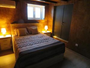 a bedroom with a bed with two lamps and a window at Casa do Cortinhal in Covilhã