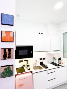 cocina con armarios blancos y nevera rosa en La Placita Boutique Trinidad, en Málaga