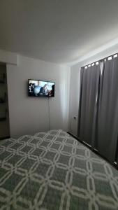 a bedroom with a bed and a television on the wall at Depto por día in San Luis