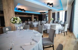 sala bankietowa z białymi stołami, krzesłami i kwiatami w obiekcie Hotel Limanova w Limanowej