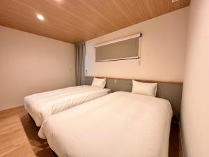 Dos camas en una habitación pequeña con TV. en Aoi Suite Takayama, en Takayama