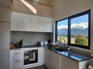 una cucina con un lavandino e una finestra con montagne coperte di neve di Alpine Retreat with a View a Glenorchy