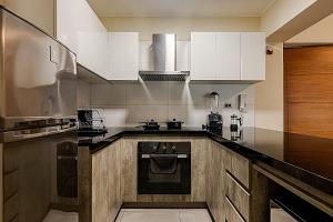 a kitchen with white cabinets and a stainless steel refrigerator at Confortable apartamento en Miraflores cerca del malecón C1 in Lima
