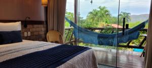 a bedroom with a bed and a balcony with a hammock at Pousada Meu Talento in Alto Paraíso de Goiás