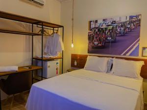 a bedroom with a bed and a desk and a painting at Kwati Villa in Parintins