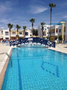 a large blue swimming pool with palm trees and buildings at Kefalonitis Hotel Apartments in Paphos City