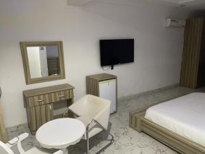 a bedroom with a bed and a chair and a tv at Ibiyemi apartment in Abuja