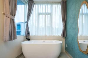 a bathroom with a large white tub in front of a window at Hoshi Apartment in Ho Chi Minh City +23 photos