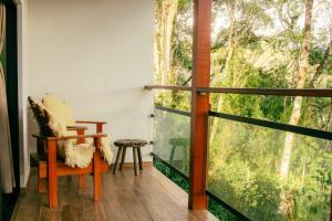 a balcony with a chair and a large window at Pousada Paraíso das Araucárias Monte Verde Vista das montanhas in Monte Verde