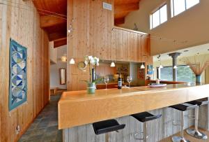 a kitchen with wooden walls and a bar with stools at Indigo Tide, True Ocean Bluff at Sea Ranch in Sea Ranch
