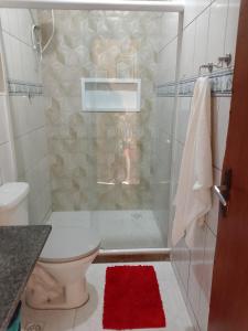 a bathroom with a shower with a toilet and a red rug at Casa Refúgio da Prainha in Arraial do Cabo +10 photos