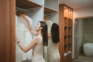 a woman looking at a dress in a closet at Villa Abigail Chiang Mai in Chiang Mai