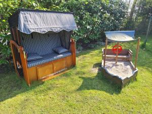 a gazebo with a chair in the grass at Ferienhaus Möwennest 18, Butjadingen, Tossens, Sauna, Strandkorb, Nordsee, 3 SZ, bis 8 Gäste plus 2 Kleinkinder in Butjadingen