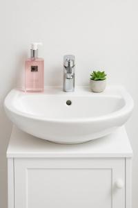 a white sink with a bottle of soap and a plant at Fribourg Studio Home in Fribourg