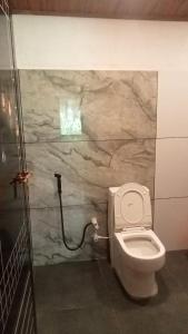 a bathroom with a toilet and a stone wall at Vihara Mud House in Marayoor