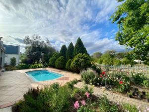 a swimming pool in a garden with flowers and trees at Karoo Escape in Oudtshoorn