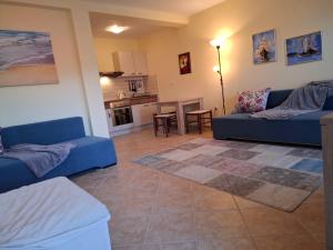 a living room with two blue couches and a kitchen at Apartment Bigovo in Tivat