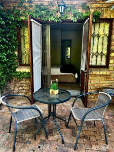 a patio with a table and two chairs and a bed at Naby-My Stellenbosch Cottage in Stellenbosch +17 photos