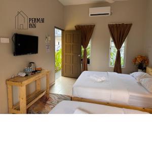 a bedroom with two beds and a flat screen tv at Roomstay Homestay Permai Inn Pekan in Pekan