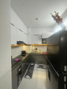 a kitchen with white cabinets and a black refrigerator at Home Love Nam Long 2 in Can Tho