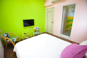 a green room with a bed and chairs and a television at Dream Homestay in Huxi