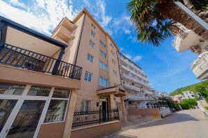 a tall building with a palm tree in front of it at Azzuro apartments Budva in Budva