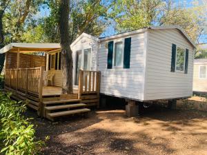 a white tiny house sitting next to a tree at Mobil-home in Agde