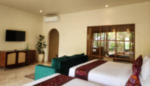 a bedroom with two beds and a tv and a couch at Sapodilla Ubud in Ubud