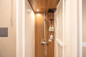 a shower in a bathroom with a wooden wall at Kstyle Apartments UNO in Tamano +122 photos