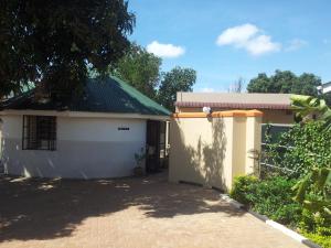 una pequeña casa blanca con entrada de ladrillo en Dich Comfort Hotel - Main Branch en Gulu