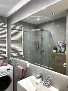 a bathroom with a shower and a sink and a washing machine at Downtown Apartments Podpromie Monica with UNDERGROUND PARKING in Rzeszów