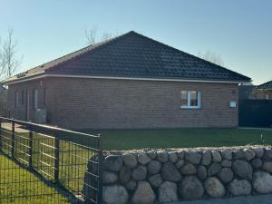 a brick house with a fence and a stone wall at Ferienhaus RELAX in Büsum