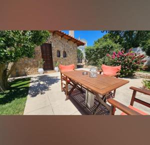 a wooden table and benches in front of a house at Garden's House in Spata