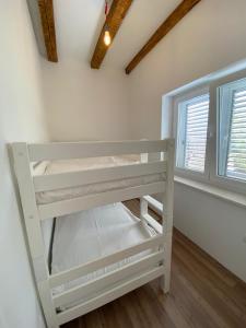 a white bunk bed in a room with two windows at Sweet holiday house in Veli Iž