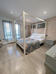a bedroom with a canopy bed and wooden floors at 1 or 2 bedroom Hot tub Lodges in North Walsham