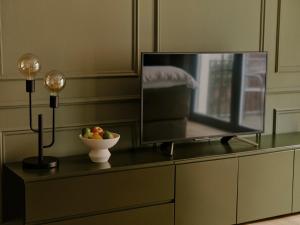 ベルリンにあるArt Apartmentsのドレッサーの上にはフルーツのボウルが置かれたテレビがある