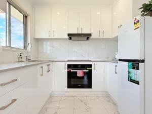 a kitchen with white cabinets and a black oven at Family Comfort Modern 3BR Retreat in Brisbane