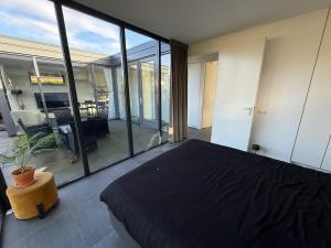 a bedroom with a bed and large glass windows at Modern bungalow with cinema in Ermelo