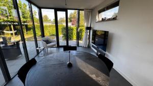 a living room with a table and a large window at Modern bungalow with cinema in Ermelo